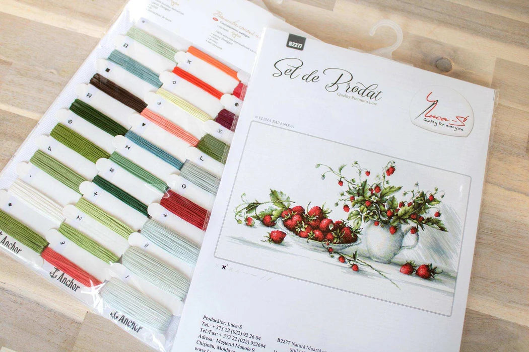 Set of embroidery threads and design sheet on a wooden surface