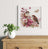Decorative painting of birds and flowers on a wall above a wooden cabinet with a vase of greenery.