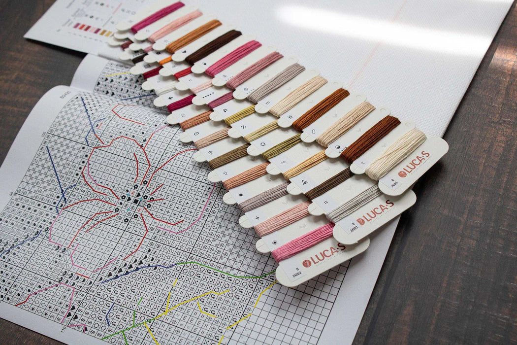 Set of embroidery thread samples with a cross-stitch pattern on paper