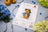 Cross stitch kit with a duck design on a table with flowers and embroidery hoop.