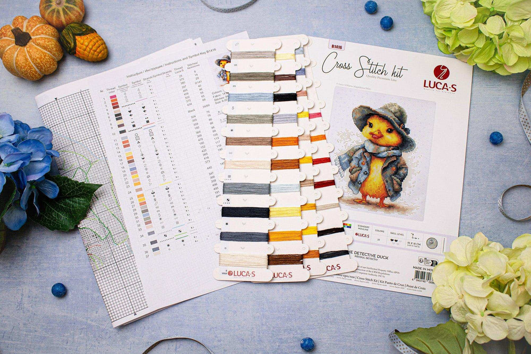 Cross stitch kit with color chart and duck design on a table with flowers and pumpkins.