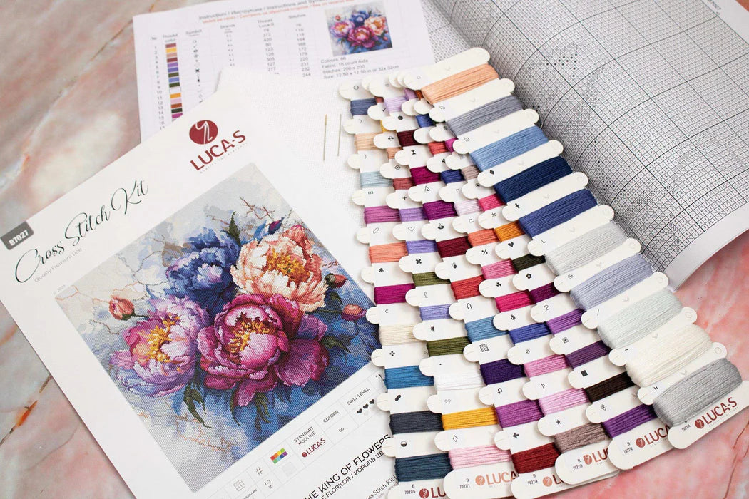 Color swatch book with embroidery floss and cross stitch pattern on a marble surface