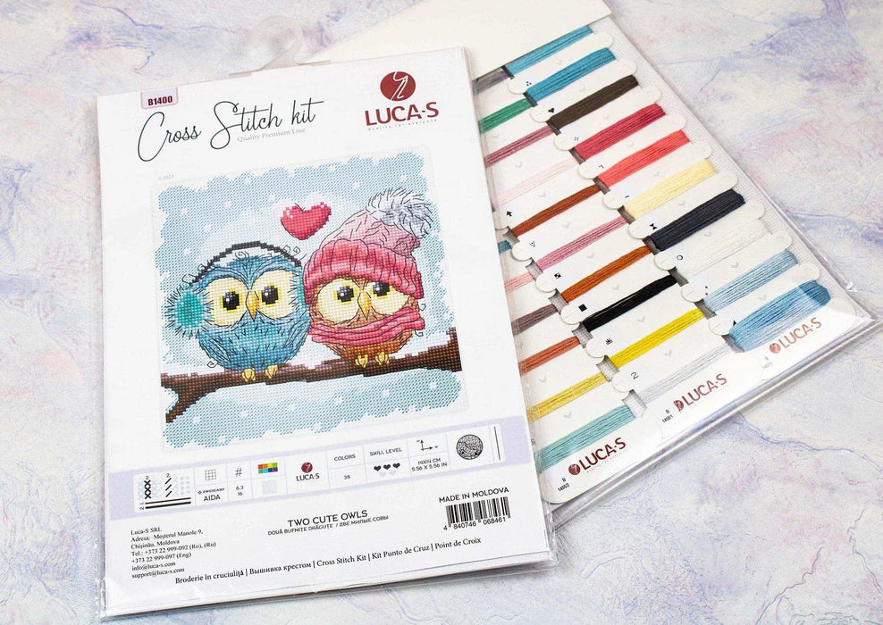Cross stitch kit with owl design and color chart on a light background