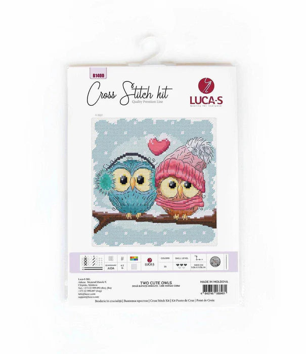 Cross stitch kit packaging with two owls wearing hats on a white background