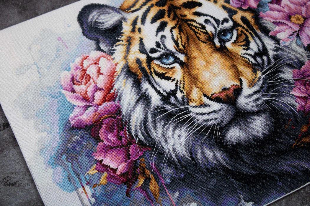 Cross-stitched tiger with flowers on a fabric background